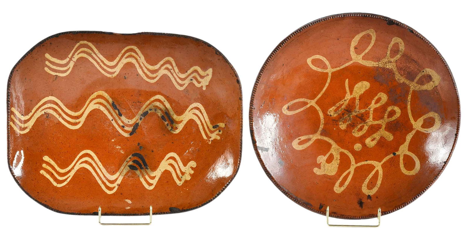 Two Large Early American Slip Decorated Redware Dishes: late 18th to early 19th century, likely made in Pennsylvania, one circular, 2-1/4 x 13-1/4 x 13-1/4 in.; one of rounded rectangular form, 2-3/4 x 15 x 12 in. Provenance: Estate of Joe and Betsy Byerly