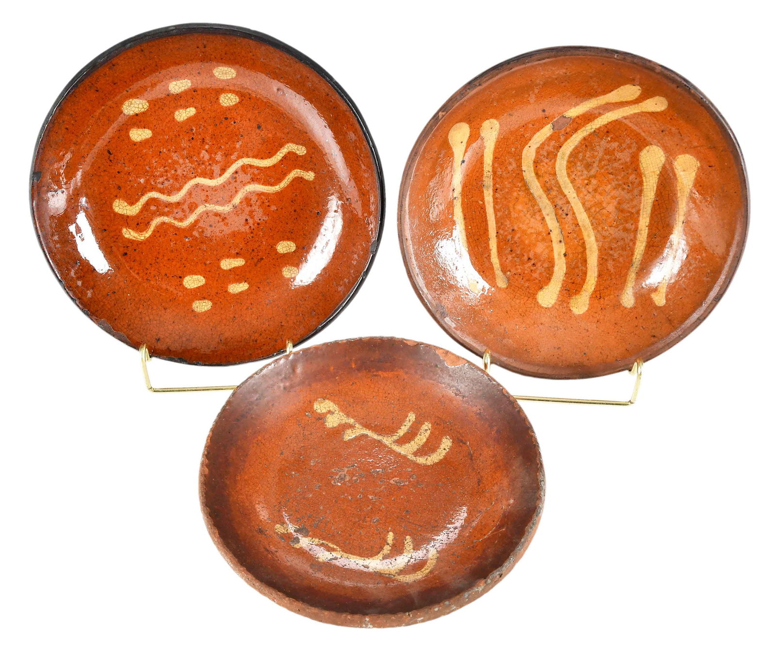 Three Early American Slip Decorated Redware Plates: late 18th to early 19th century, likely made in Pennsylvania, each of similar form with wavy line slip decoration, largest 1-1/4 x 7-3/4 in. Provenance: Estate of Joe and Betsy Byerly, Greensboro, Nor
