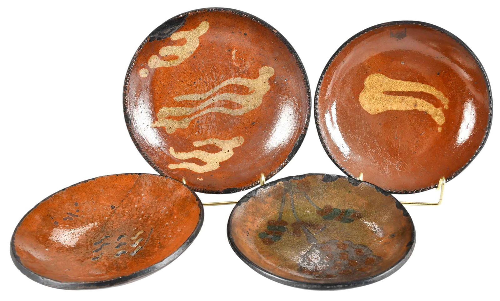 Four Early American Slip Decorated Redware Plates: late 18th to early 19th century, likely made in Pennsylvania, each of similar form with line and figural decoration, largest 1-1/2 x 7-3/4 x 7-3/4 in. Provenance: Estate of Joe and Betsy Byerly, Green