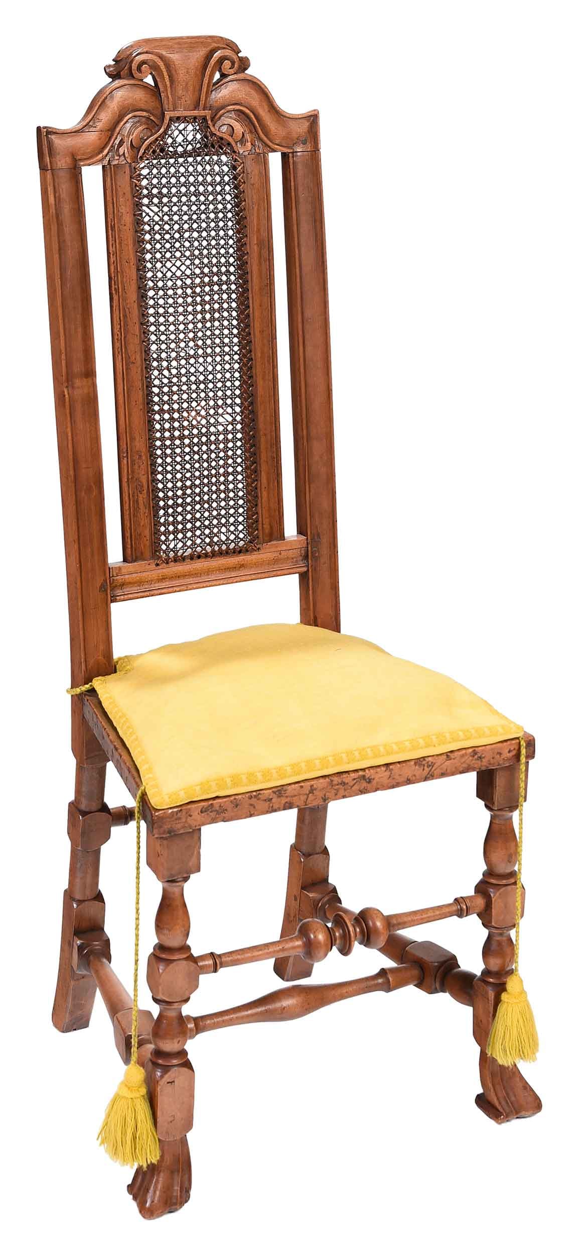 Fine and Rare Boston William and Mary Cane Back Side Chair: Massachusetts, 1710-1730, a fine example of the form, leaf carved and scrolled crest, turned legs and stretchers with boldly formed Spanish feet, the seat set with a chrome yellow loose cushion, 46 x