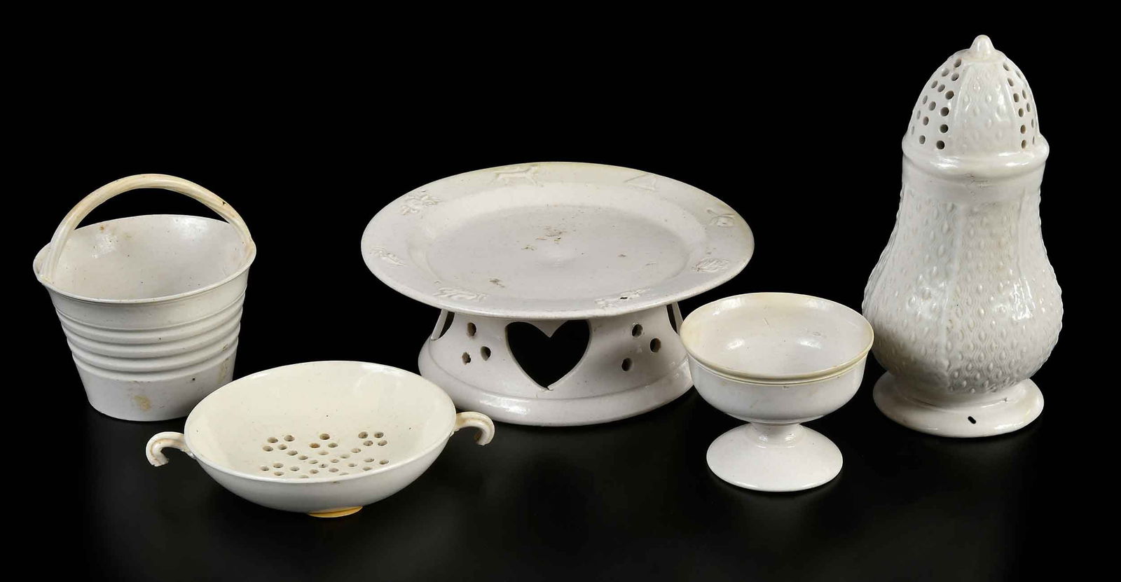 Five Pieces Staffordshire Salt Glazed Teaware: English, 18th century, comprising: tea strainer; caster; small goblet; bucket; stand with pierced foot; largest 1-7/8 x 5-1/4 x 5-1/4 in. Provenance: (all but caster) Wynn A. Sayman, Richmond, Massach