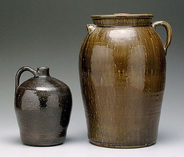 Lanier Meaders stoneware jug, churn: Lanier Meaders stoneware jug, churn: ovoid jug, medium olive glaze, 10 in., (two 1/4 in. rim chips); four-gallon churn and lid, runny medium olive glaze, 16 in., (crack and small chips on edge of lid)