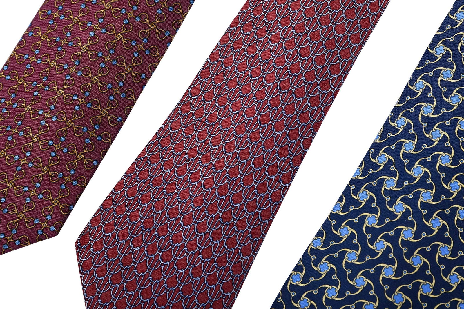 Three Hermes Silk Ties, Burgundy and Navy: France, each tagged "100% silk/dry clean only", burgundy/silver 55 x 3-1/4 in.; burgundy/gold 55 x 3 in.; navy 55-1/2 x 3-1/2 in.Provenance: Private Collection