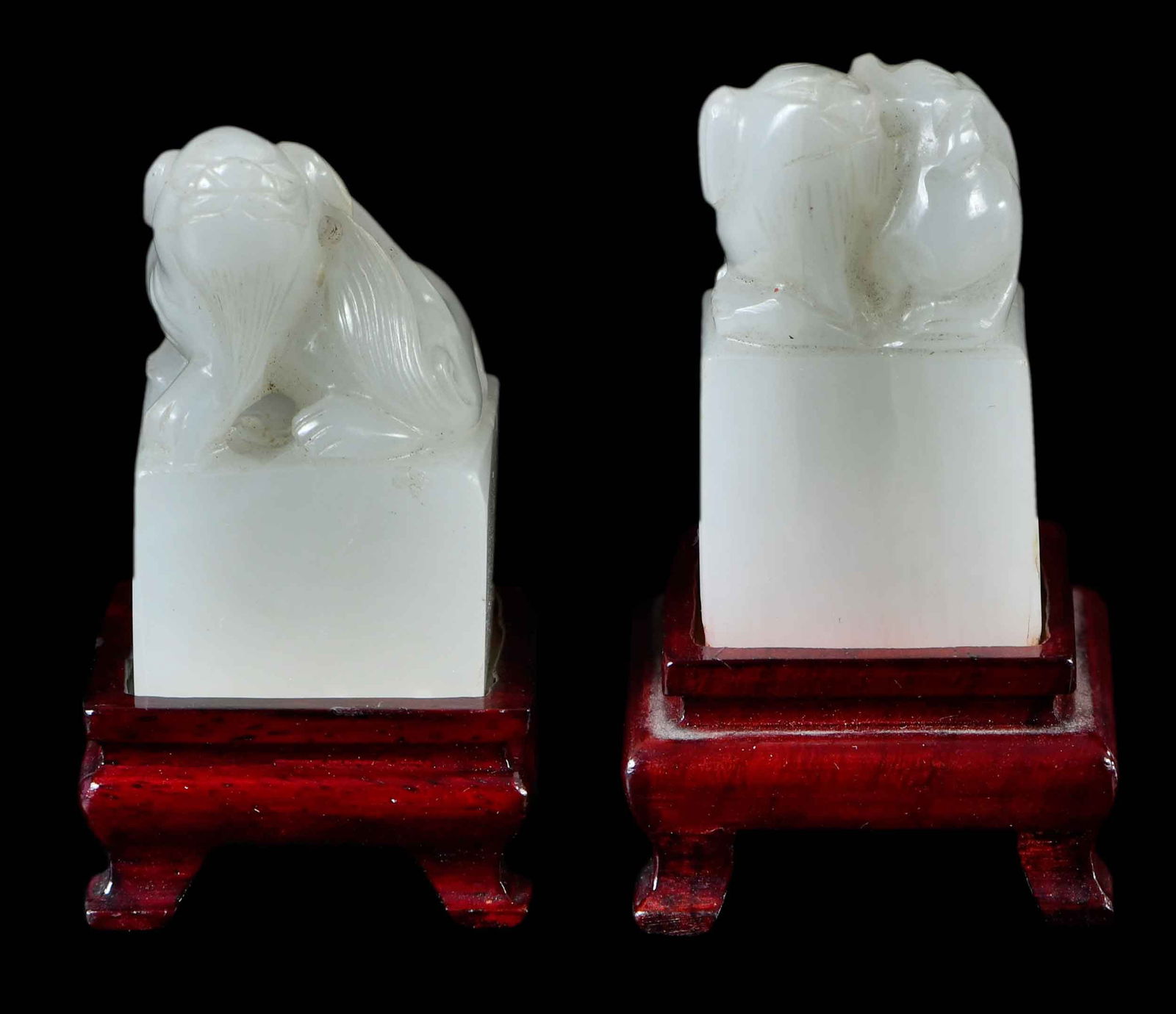 Two Diminutive Chinese Carved White Jade Seals: each of square form with fu lion finial, with conforming stand, larger 1-1/2 x 3/4 x 1-1/2 in., larger height on stand 2-1/4 in.Provenance: The Lifetime Collection of Ronald Elliott Hasbrouck