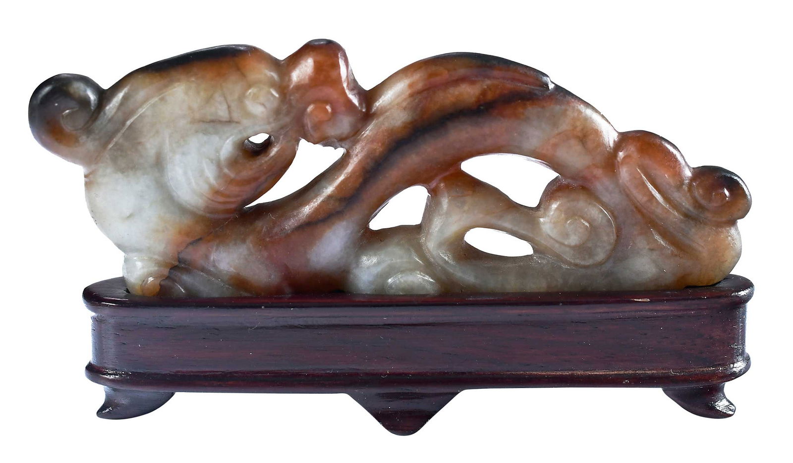 Chinese Carved Jade Stylized Dragon Figure on Stand: white to russet and dark brown body, 1-1/4 x 3-1/4 x 1/4 in., with conforming wood stand, height on stand 1-3/4 in.Provenance: The Lifetime Collection of Ronald Elliott Hasbrouck Woodaman