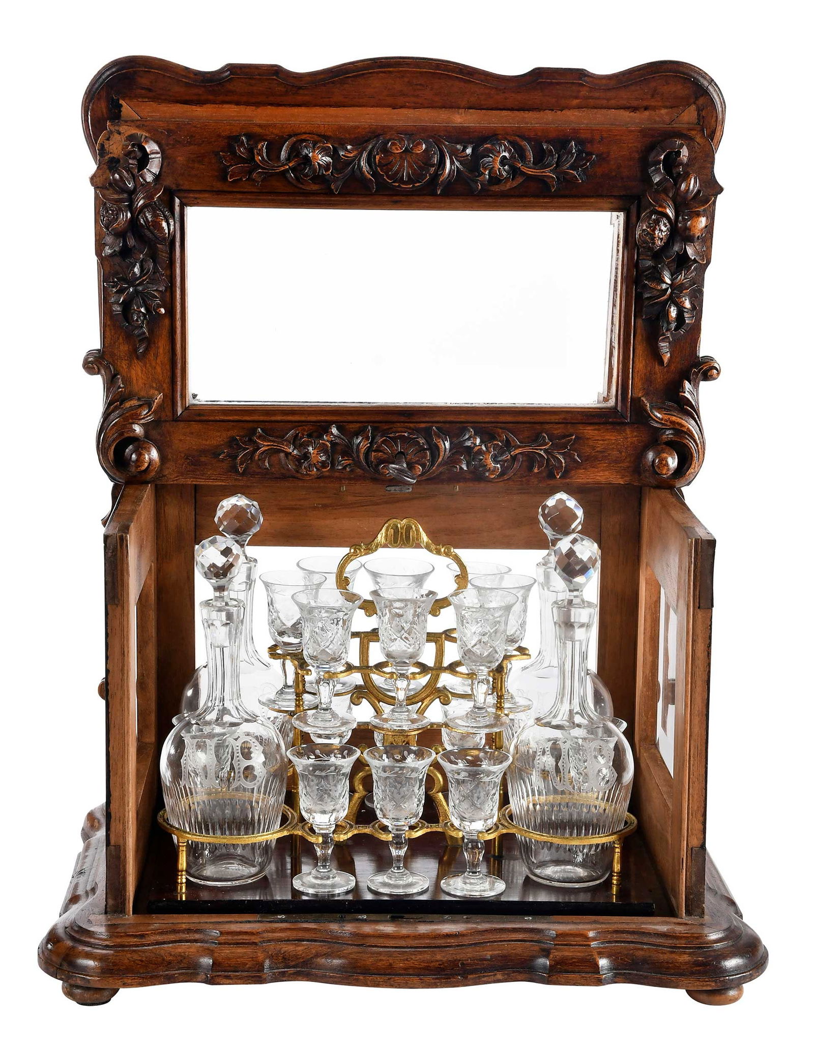 French 19th Century Carved Walnut Tantalus Box with Drinkware: floral and foliate carved case with beveled glass sides housing fitted gilt metal carrying frame, four glass decanters monogrammed "NB", and sixteen cordials, on bun feet, with key, 11-1/2 x 15-1/2 x