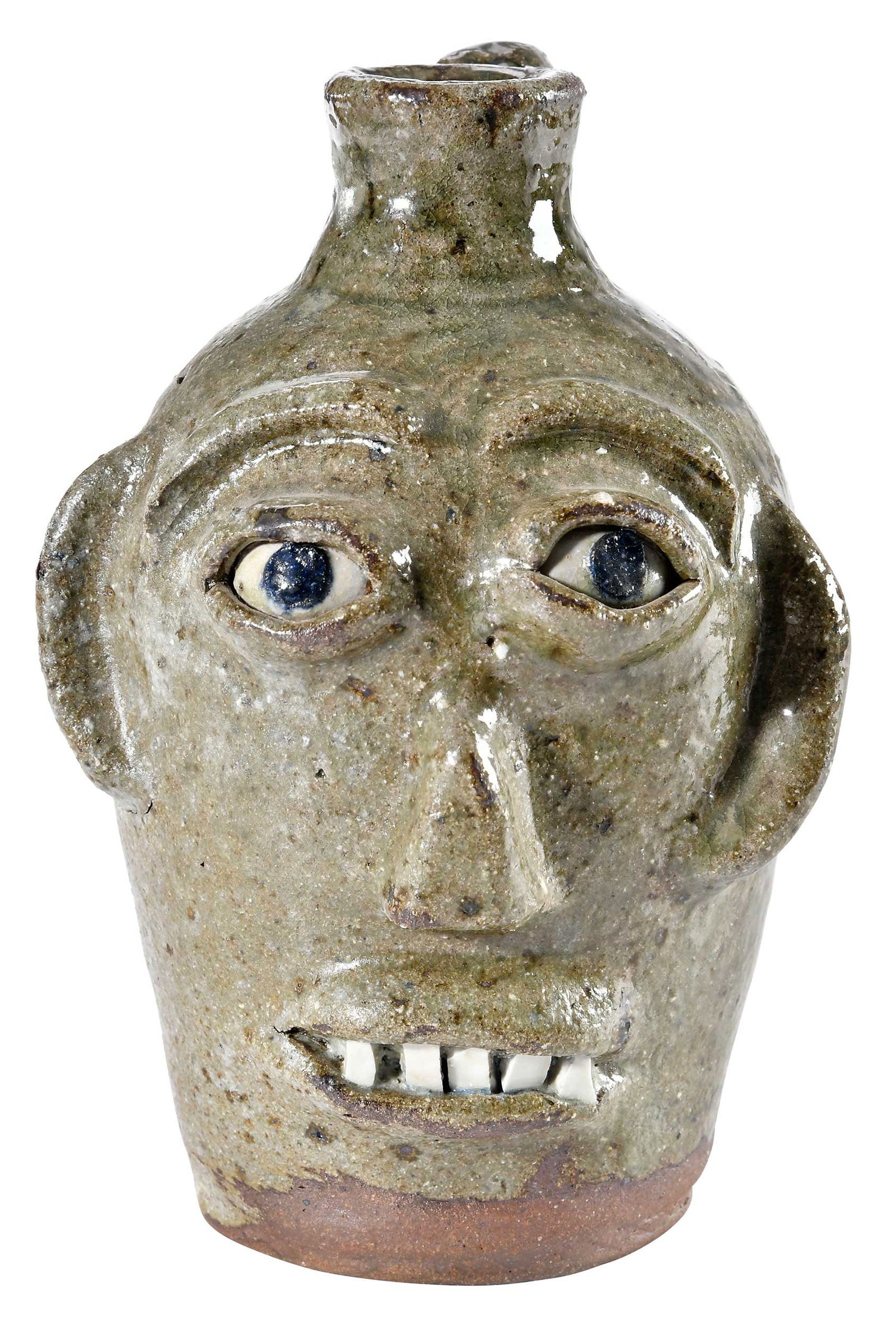 Small Burlon Craig North Carolina Stoneware Face Jug: (Vale, North Carolina, 1914-2002) speckled light olive green alkaline glaze, applied facial features, white clay inset eyes with cobalt pupils, broken china teeth, incised wavy line decoration through