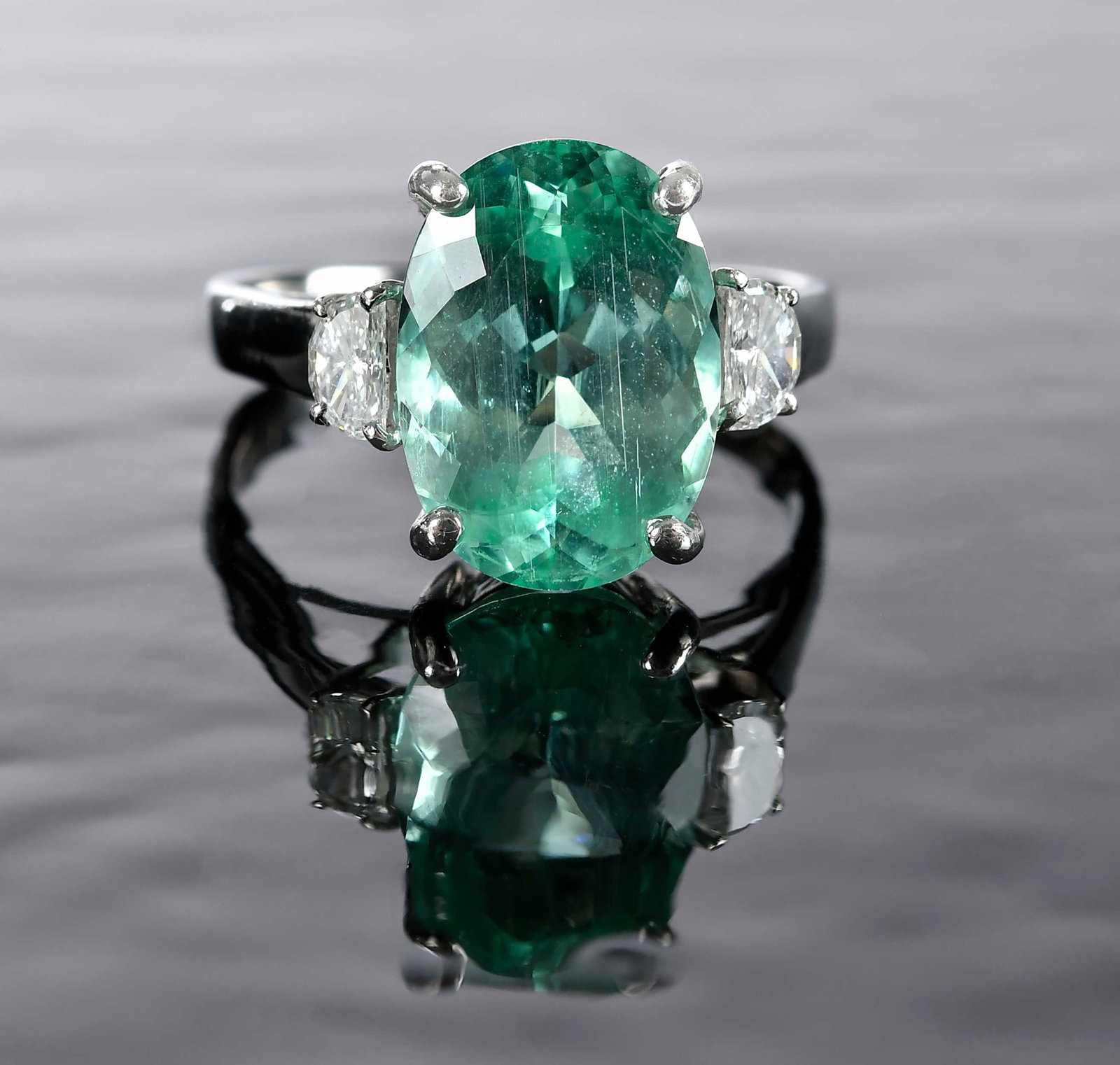 Platinum Paraiba Type Tourmaline and Diamond Three Stone Ring - GIA: center oval faceted Mozambique Paraiba type tourmaline, approx. 14.13 x 10.14 x 7.00mm, 6.60ct., GIA # 2235922627, two half moon faceted diamonds, 0.41ctw., VS, G-H, marked "Rhapsody, PT950, 6.60, D0.