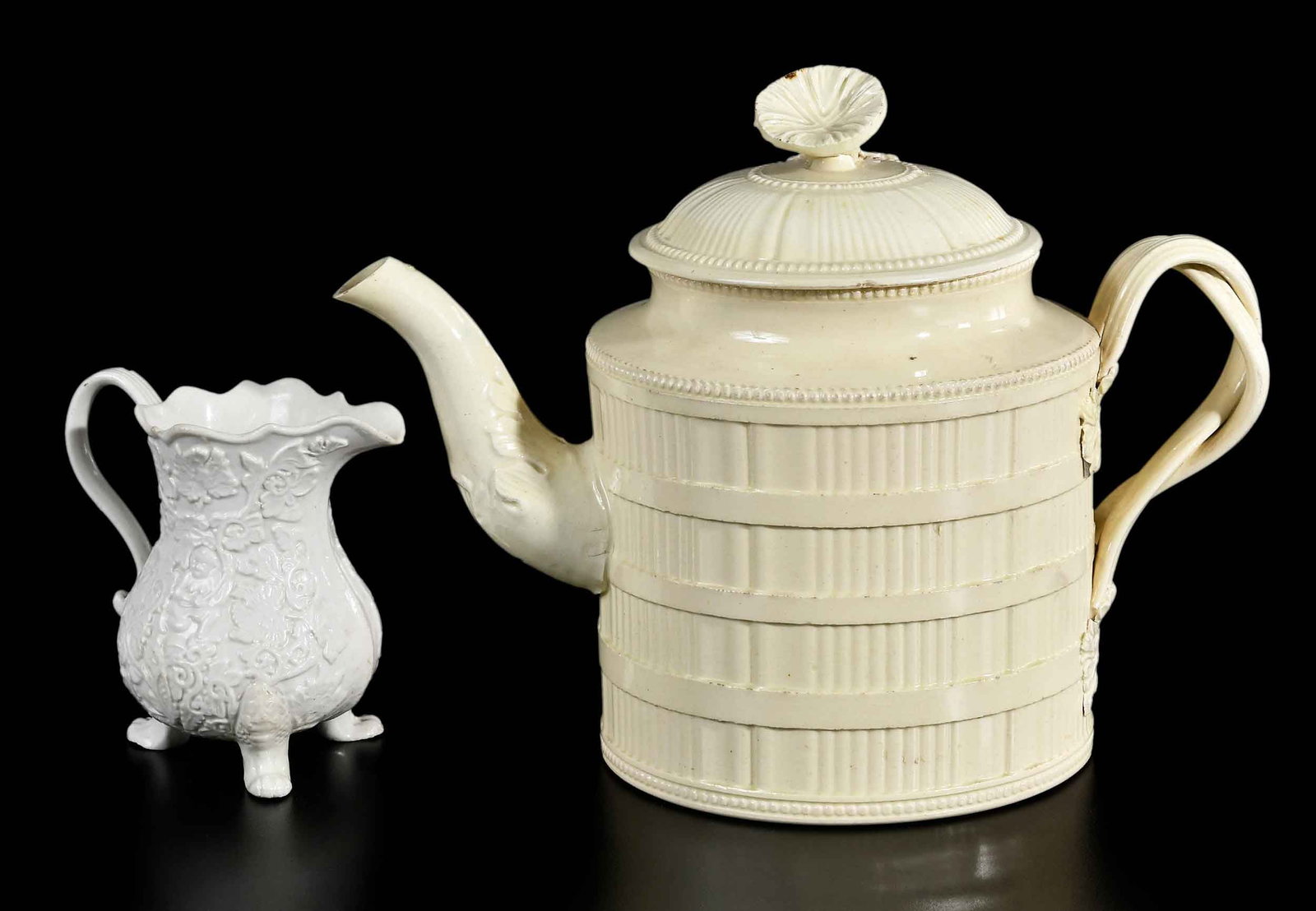 Two Pieces English Staffordshire Teaware, Horne & Atkins Provenance: mid 18th century, comprising: creamware teapot with twisted branch form handle and foliate decoration, 6-1/2 x 8-1/2 x 4-3/8 in.; molded stoneware jug with "boy in the bushes" pattern decoration, 3-1/