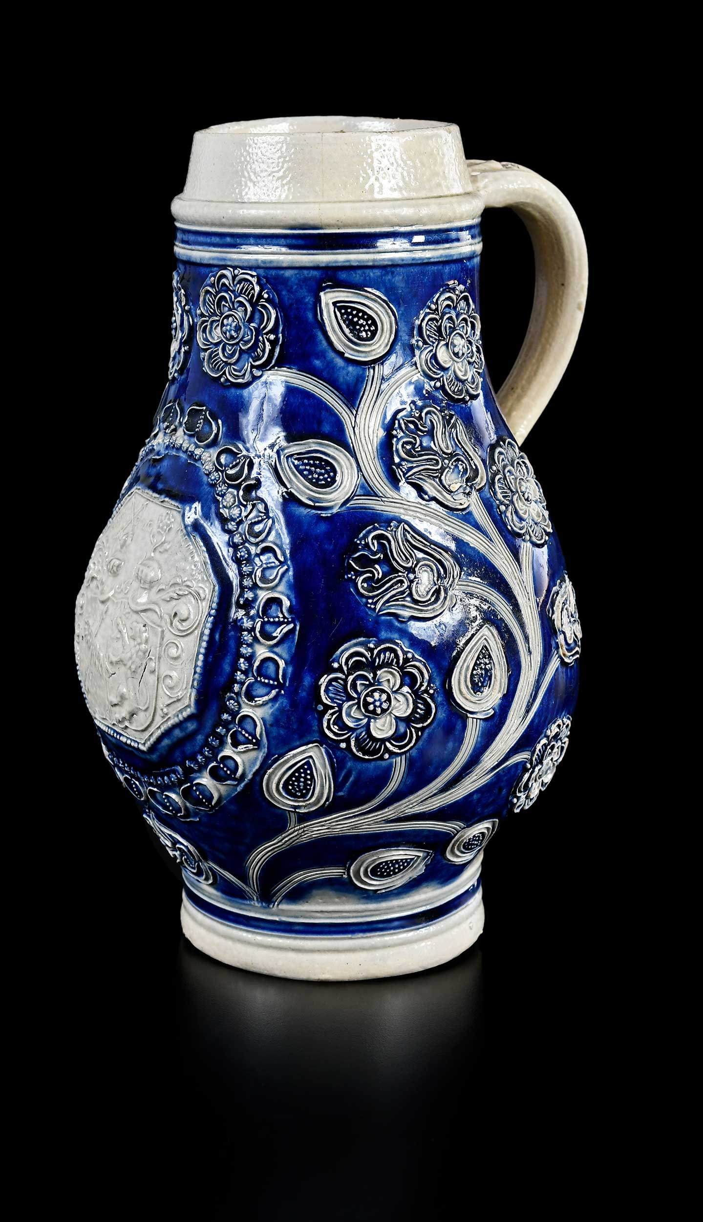 Large Westerwald Salt Glazed Stoneware Jug: German, 18th century, floral and vine sprigging centering armorial medallion with lettering "Iohan / Georg / Rheindorf", 9-3/4 x 6-1/2 x 5-3/4 in. Provenance: From the Collection of Elbert H. Parsons,