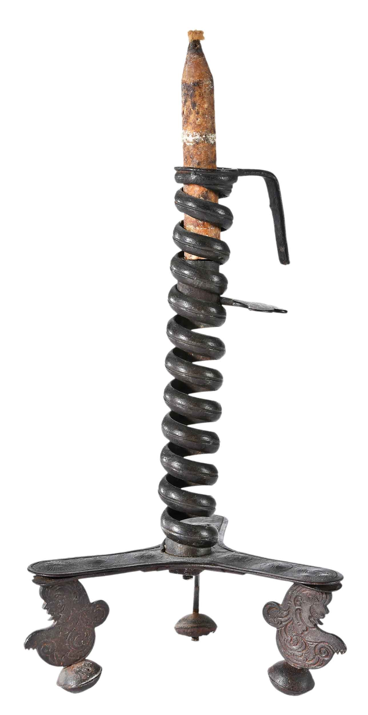 Early Wrought Iron Adjustable Candle Holder, Joe Kindig Provenance: probably Continental, 18th century, courting or spiral candleholder, with antique and probably period candle, engraved tripod base with dolphin feet, 9-1/2 x 5-1/2 x 5-1/2 in. Provenance: Joe Kindig A
