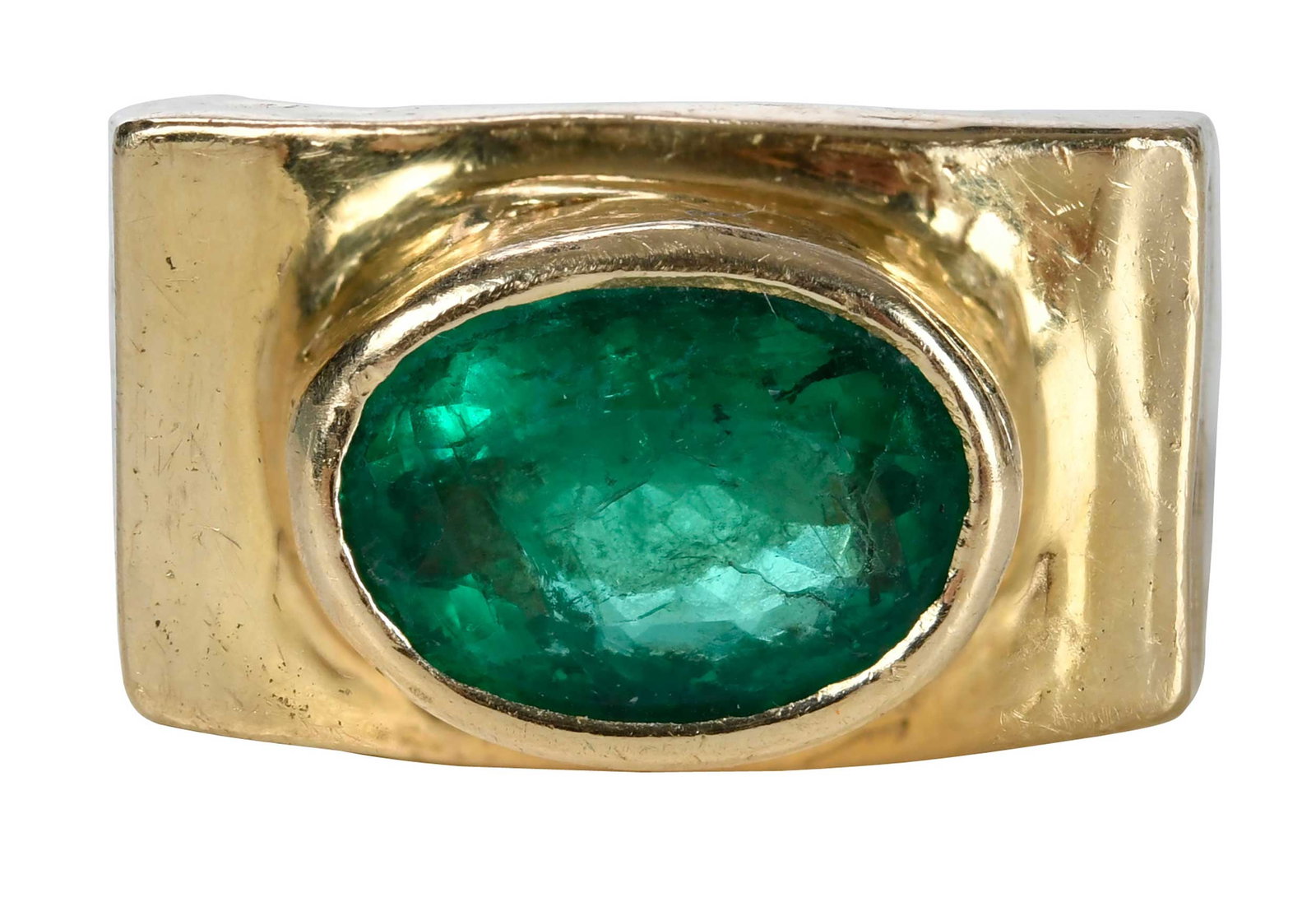 14kt. Horizontal Bezel Set Emerald Ring: oval faceted emerald, hammered finish, marked "14K", yellow gold, 6-1/2 ring sz., 11.5mm wide, 15.5 g Provenance: Collection of Dr. George and Connie Manger Note: Brunk Auctions makes no warranty or g