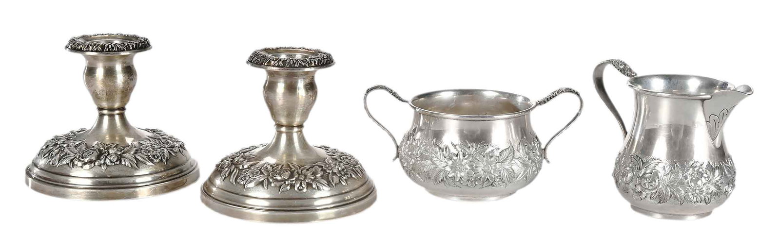 Four Pieces Kirk Repousse Sterling Hollowware: American, 20th century, including creamer, 3-1/4 in.; open sugar, 2-3/4 x 5-1/4 x 3-1/2 in.; pair of weighted candlesticks, 3-1/2 x 4-1/4 in., 8.7 oz. T. excluding weighted pieces Provenance: Collecti