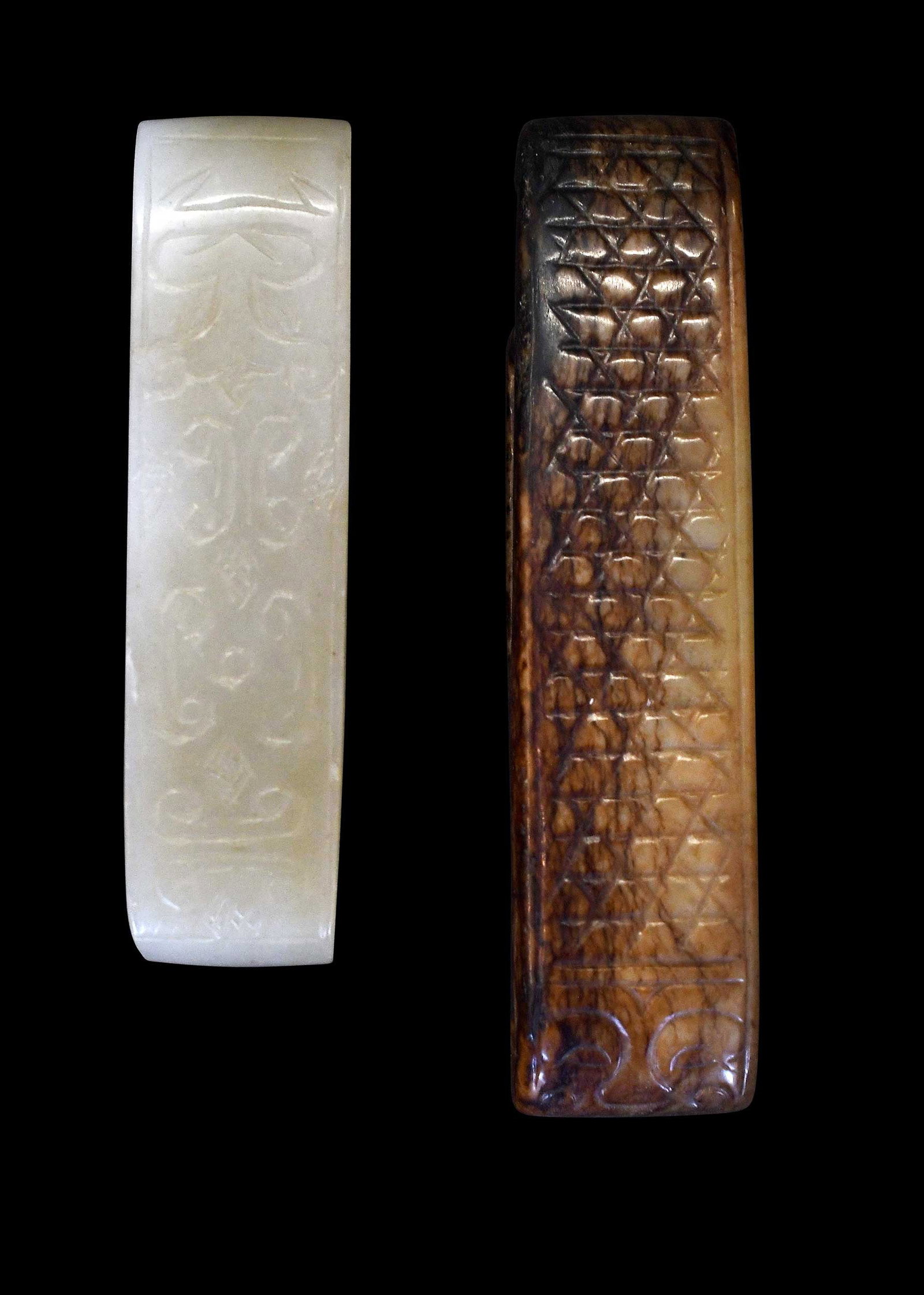 Two Chinese Carved Jade Sword Fittings: comprising: pale green with engraved scrolling decoration, 3 x 3/4 x 5/8 in.; pale green with russet inclusion, engraved crosshatch and taotie mask, 3-5/8 x 7/8 x 1/2 in. Provenance: The Collection of
