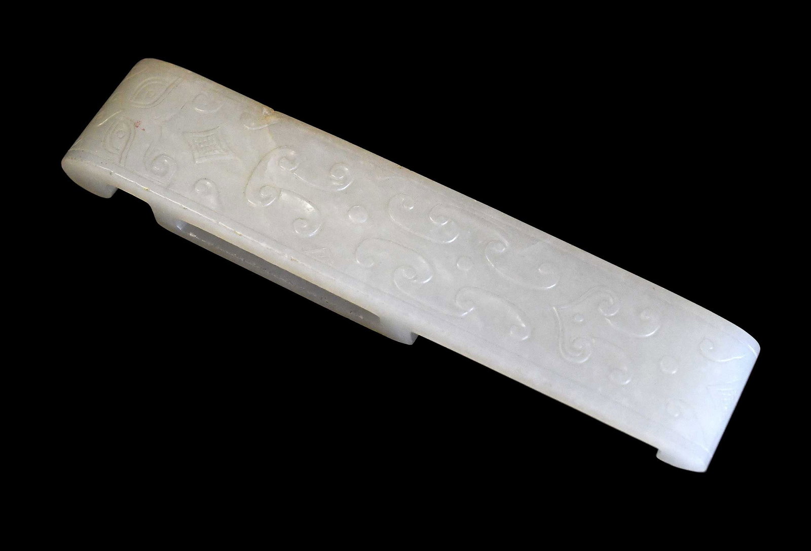 Chinese Carved Jade Sword Fitting: pale green with whitish inclusions, incised taotie mask and scrolled decoration, 4-5/8 x 1 x 1/2 in. Provenance: The Collection of William S. Arnett, Atlanta, Georgia; sold to benefit Tinwood Foundati