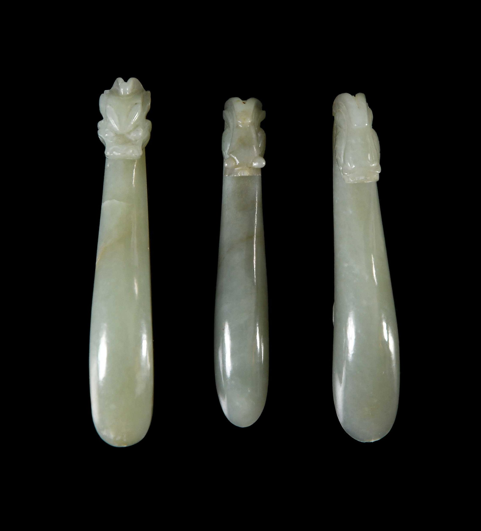 Three Chinese Carved Green Jade Belt Hooks: each light olive green with carved dragon/chilong head, largest 3-3/4 x 3/4 x 7/8 in. Provenance: The Collection of William S. Arnett, Atlanta, Georgia; sold to benefit Tinwood Foundation Note: These 