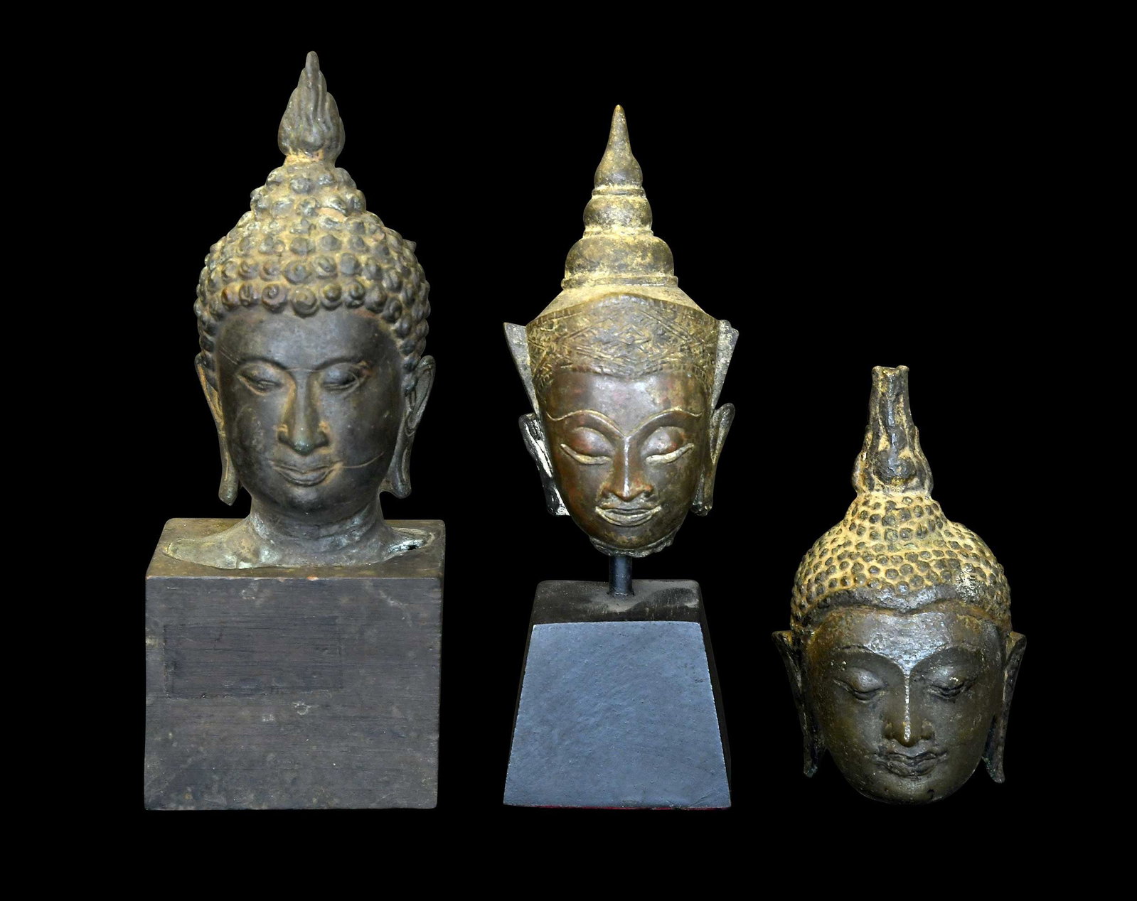 Three Miniature Southeast Asian Bronze Buddha Heads: probably Thai, possibly 16th-18th centuries, two mounted on wood bases, largest 7-1/4 x 2-3/4 x 2-1/4 in. including base Provenance: The Collection of William S. Arnett, Atlanta, Georgia; sold to bene