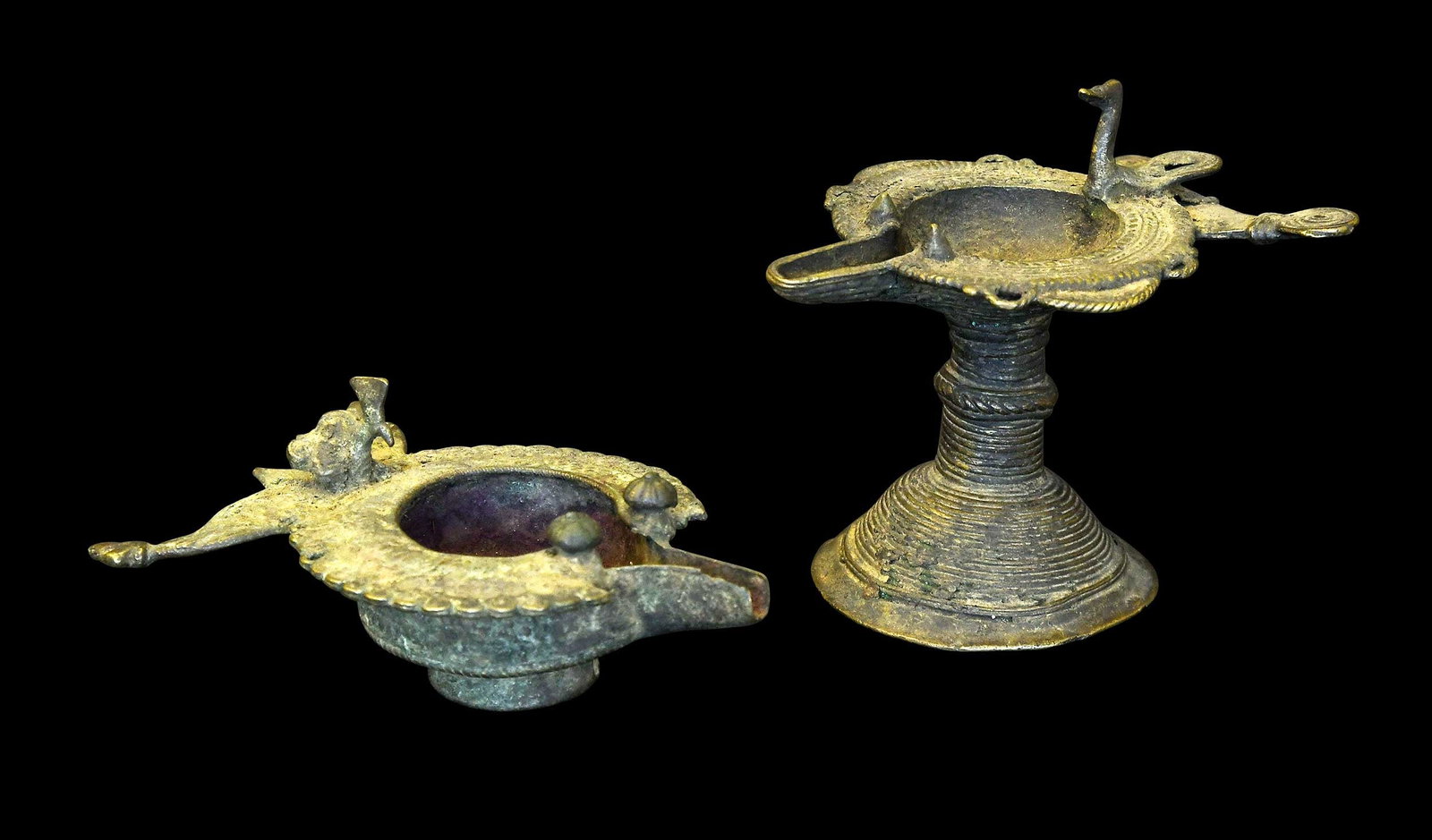 Two Indian Dhokra Diyas or Bronze Oil Lamps: possibly late 19th/early 20th century, comprising example raised on stand, 4-1/2 x 5 x 3-3/4 in.; example with round foot, red interior, 2-1/4 x 3-5/8 x 5-3/8 in.; both with small birds Provenance: Th
