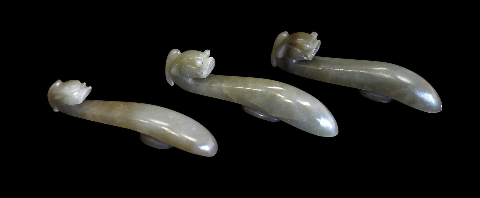 Three Chinese Carved Jade Belt Hooks: all with qiulong (horned dragon) head form hooks in celadon green jade with brown and/or white inclusions, largest 3-1/2 x 3/4 x 3/4 in. Provenance: The Collection of William S. Arnett, Atlanta,
