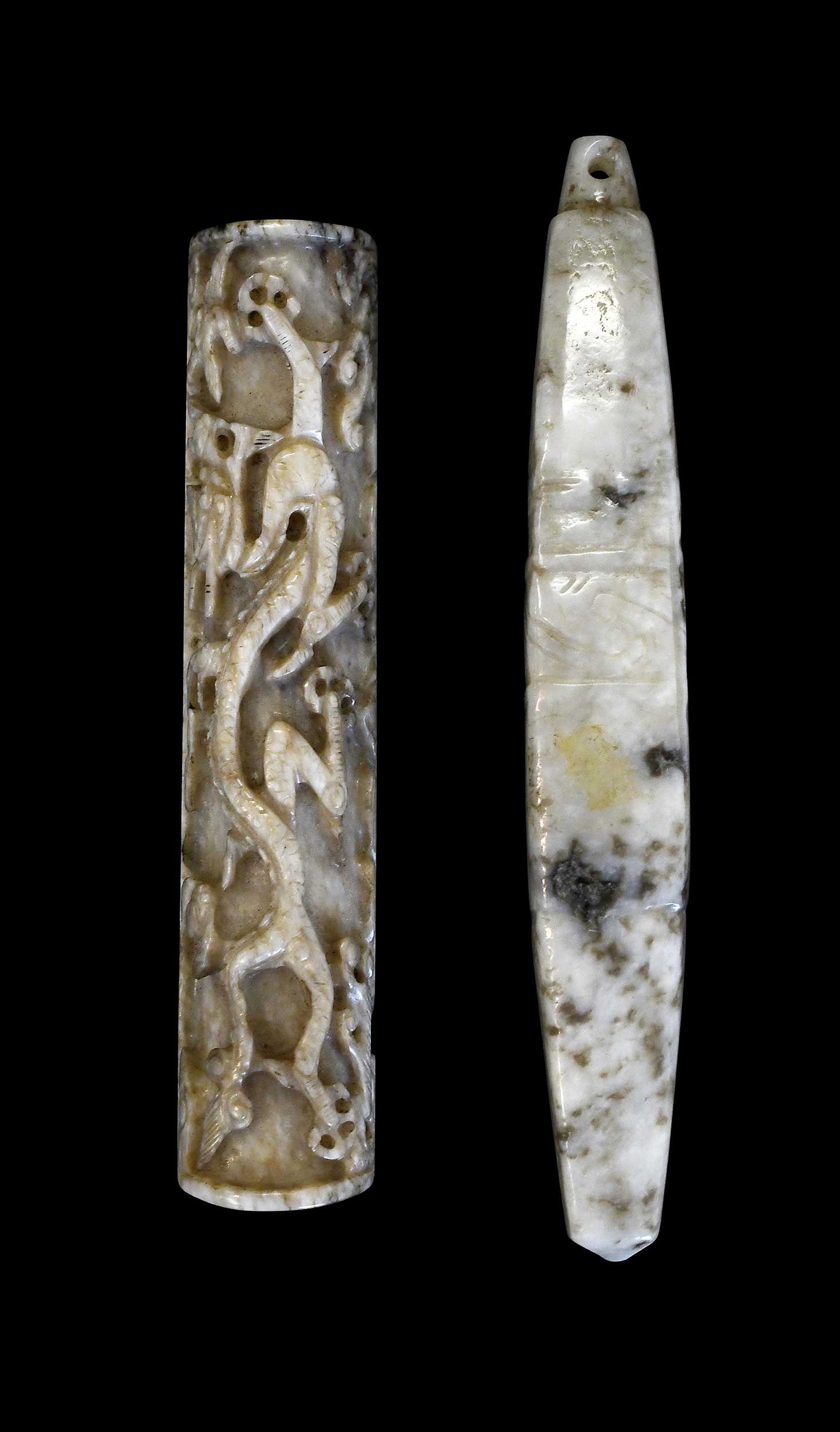 Two Chinese Carved Jade Pendants: comprising: carved dragon jade pendant, bone with brown inclusions, 3-7/8 x 3/4 x 1/2 in.; elliptical jade pendant, whitish with mottled black and gray inclusions, 4-1/2 x 5/8 x 5/8 in. Provenance: