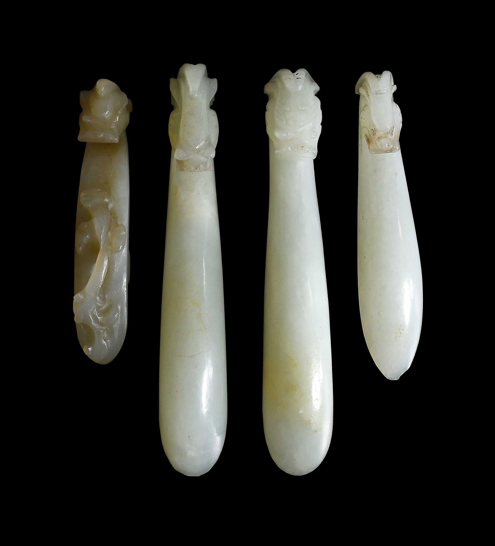 Four Chinese Carved Jade Belt Hooks: all with qiulong (horned dragon) head hooks in pale celadon jade, largest 3-5/8 x 5/8 x 7/8 in. Provenance: The Collection of William S. Arnett, Atlanta, Georgia; sold to benefit Tinwood Foundation No