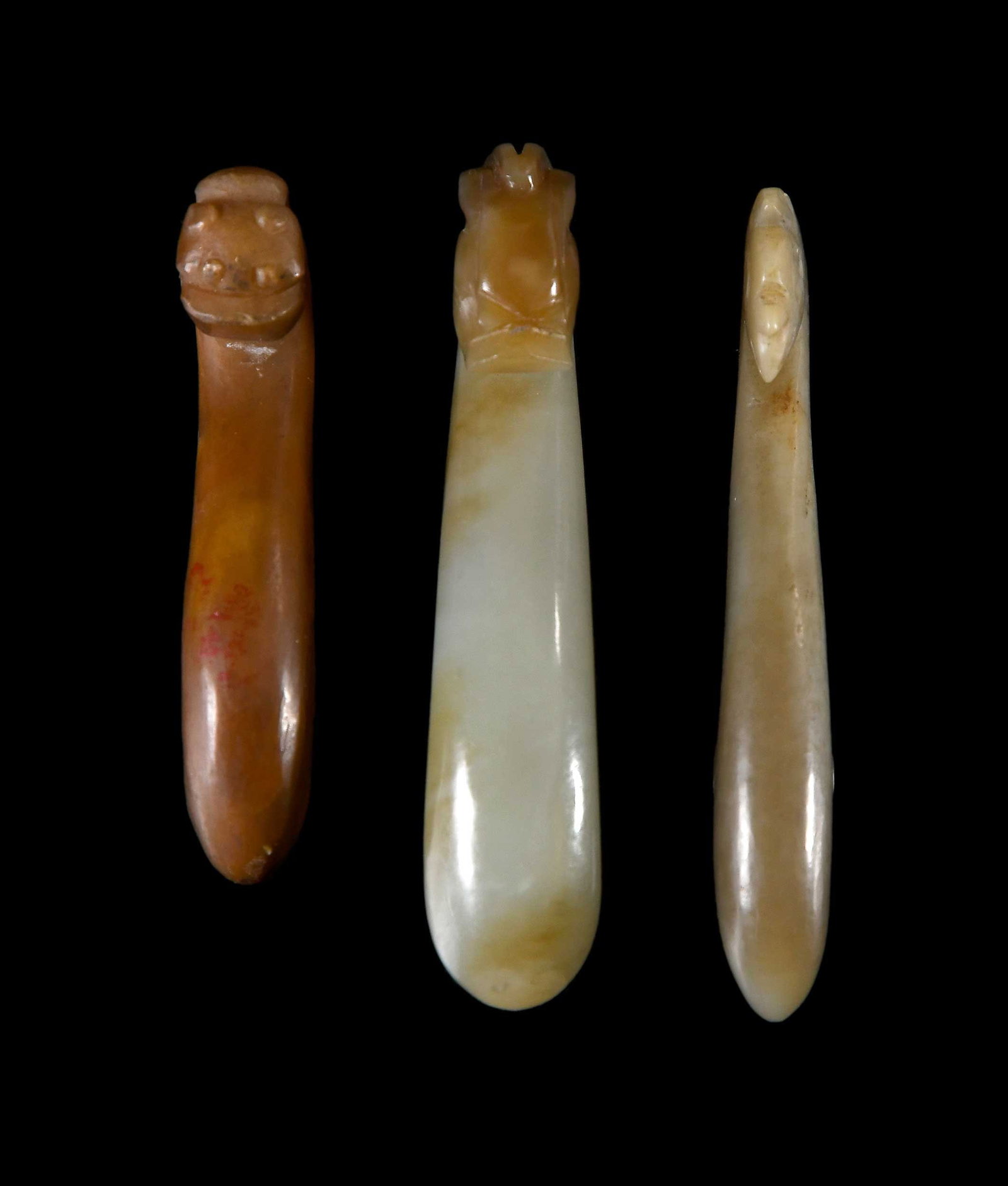 Three Small Chinese Carved Jade Belt Hooks: two pale green and one brown, each with carved dragon/chilong head, 3-3/4 x 3/4 x 1 in. Provenance: The Collection of William S. Arnett, Atlanta, Georgia; sold to benefit Tinwood Foundation Note: