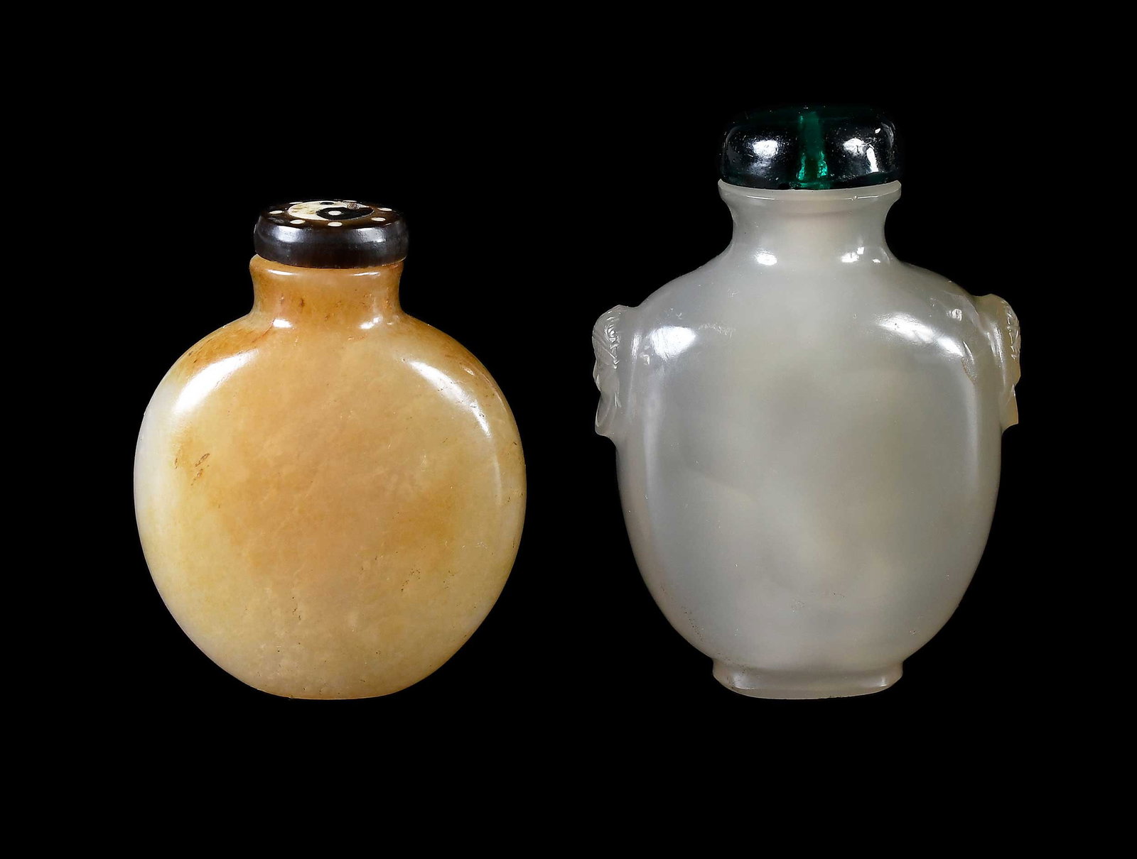 Two Chinese Carved Jade Snuff Bottles: comprising pale green or whitish jade example, mouth with everted rim, mythical beast form handles, green glass stopper, 2-3/4 x 2 x 1-1/8 in.; example with narrow rounded body, russet inclusions and 