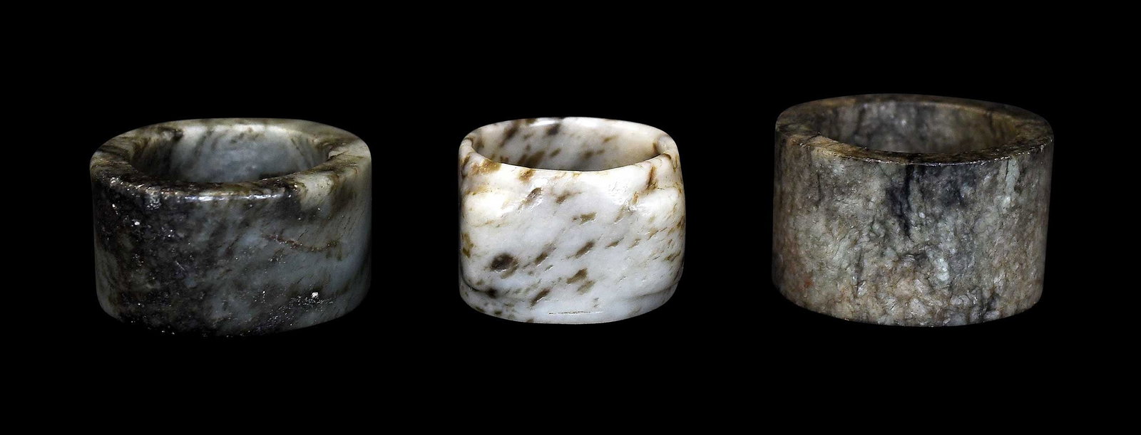 Three Chinese Carved Jade Archer's Rings: two nephrite and one jadeite, each with varied inclusions, largest 1 x 1-3/4 x 1-3/4 in. Provenance: The Collection of William S. Arnett, Atlanta, Georgia; sold to benefit Tinwood Foundation Note:
