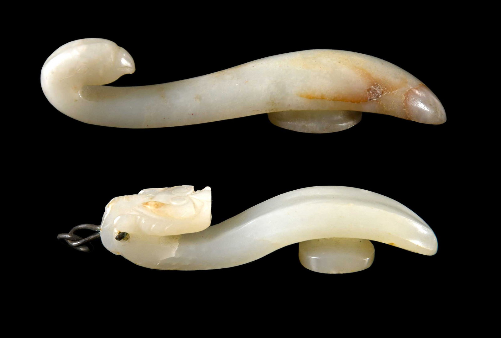 Two Jade Belt Hooks: one with qiulong (horned dragon) head hook, the other with bird head hook, both of pale celadon jade with russet inclusions, larger 3-5/8 x 7/8 x 3/4 in. Provenance: The Collection of William S.