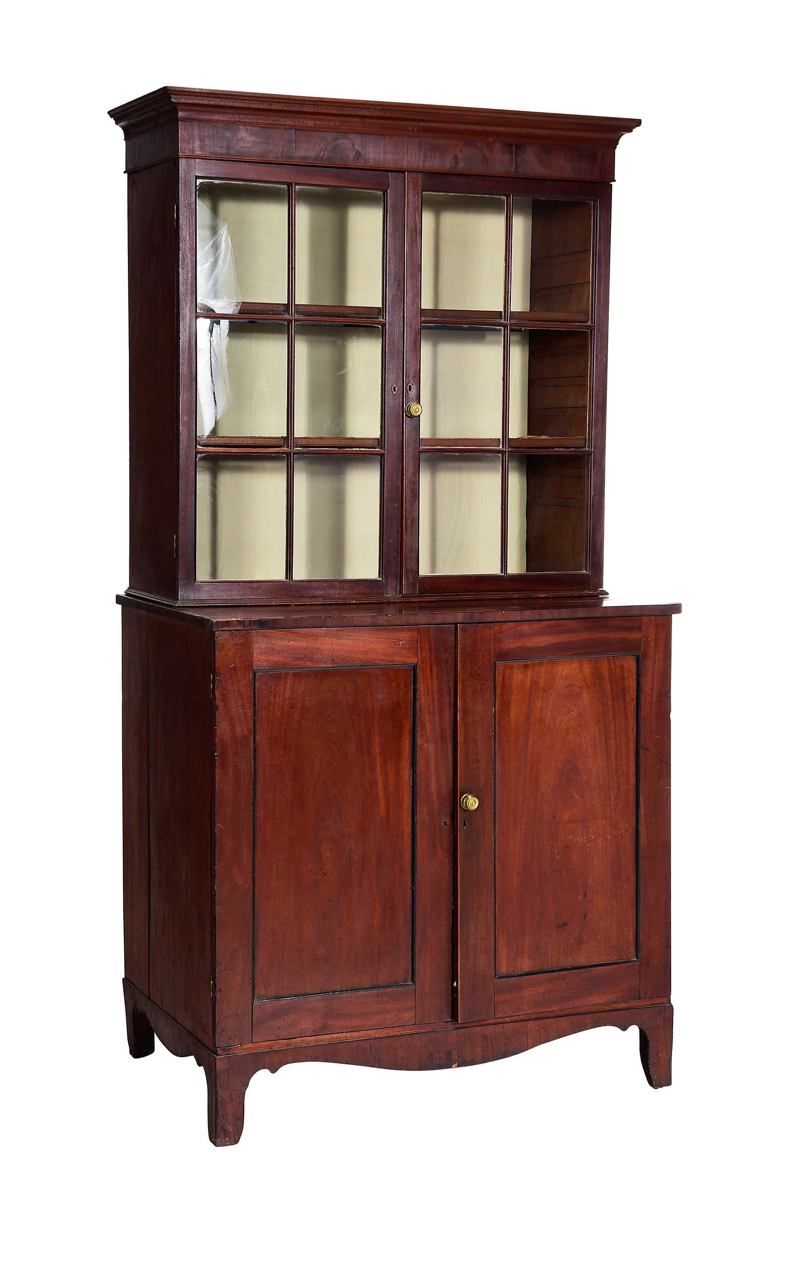 George III Figured Mahogany Bookcase Cabinet: British, late 18th century, glazed door top section with shelved interior, two door base with scoop front drawers, bracket feet and shaped apron, now electrified, 84-3/4 in. x 43-1/2 x 26-1/2 in. Prov