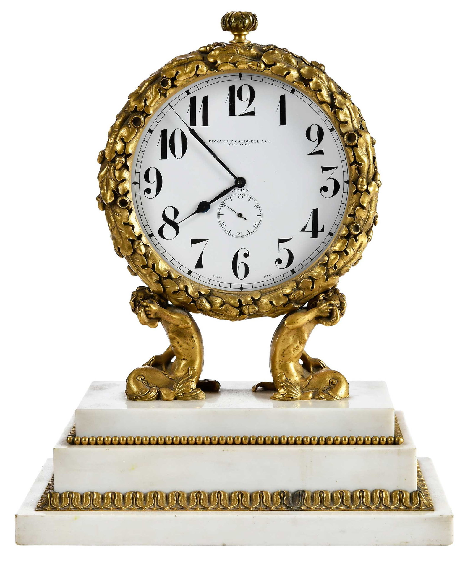 Edward F. Caldwell and Co. Gilt Bronze and Marble Desk or Mantel 8 Day Clock: late 19th/early 20th century, white enameled dial with black lettering and inscribed "EDWARD F. CALDWELL & CO. / NEW YORK", encircled in oak leaf and acorn frame held by triton figures, stepped white 