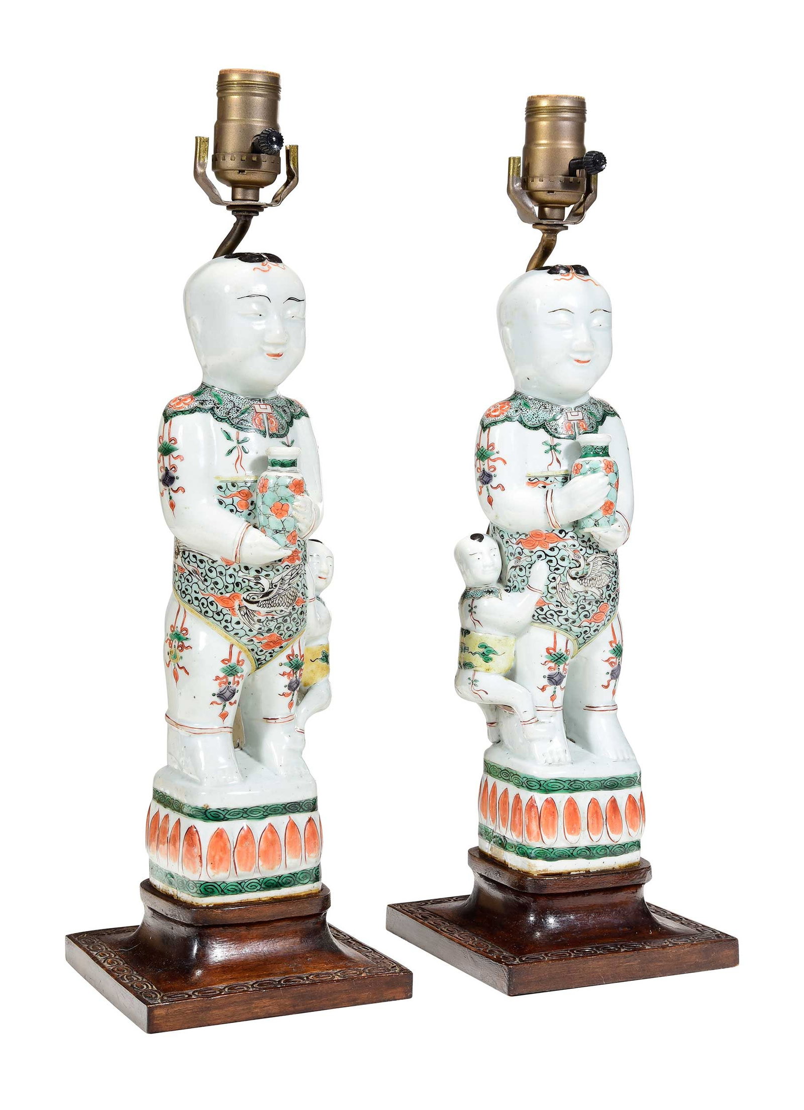 Mirrored Pair of Chinese Famille Verte Porcelain Boy Form Lamps: 19th century, possibly depicting the He-He Er Xian (Immortals of Harmony and Union), polychrome enamel decoration, carved rose quartz finials, carved wood bases, 18 x 5-1/2 x 5-1/4 in. without harps,