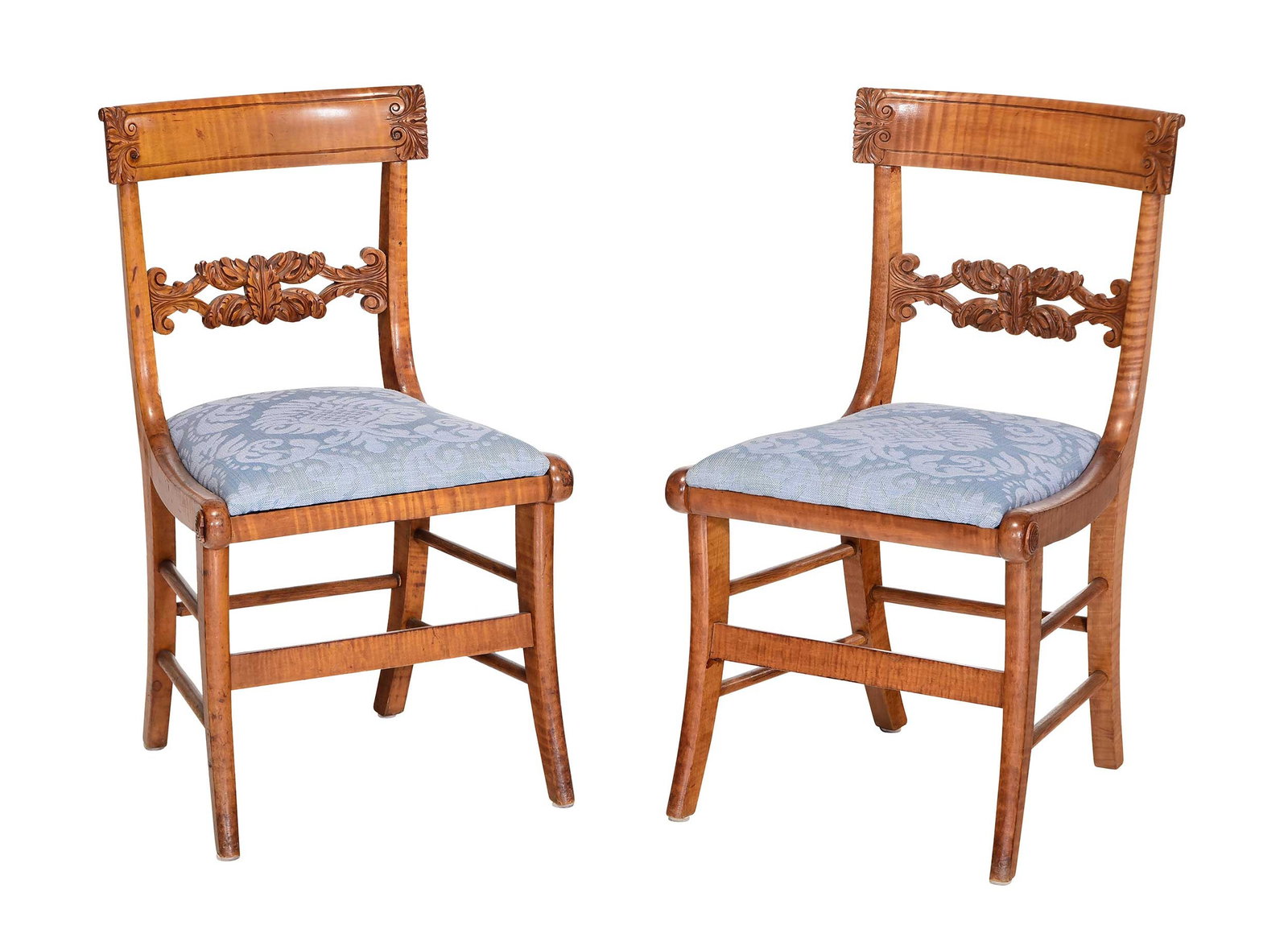 Pair American Classical Carved Tiger Maple Klismos Side Chairs: probably Philadelphia, circa 1830, scroll and foliate carved crest rail ears and splat, applied roundels to ends of front seat rail, blue foliate motif slip seats, 32 x 18-1/2 x 19 in., seat heights 1
