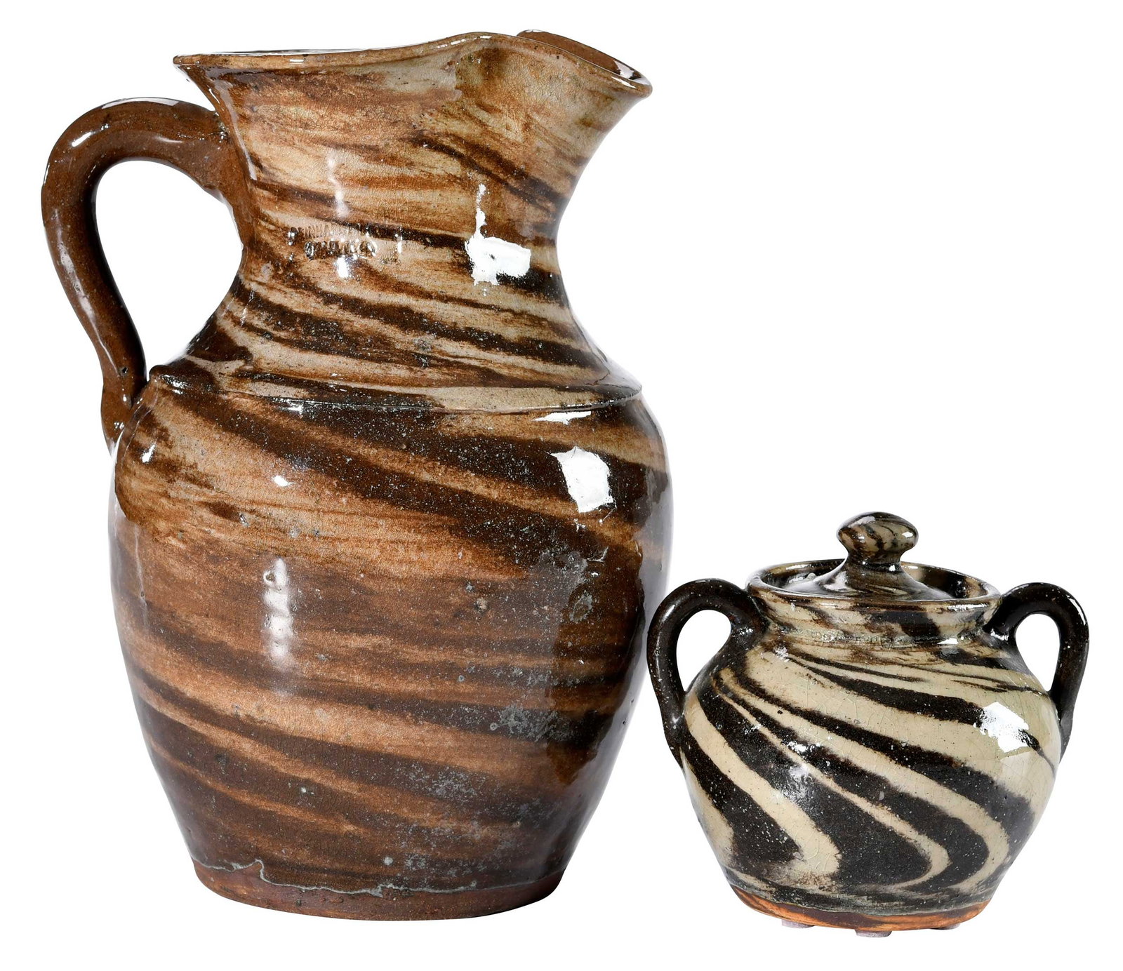 Two Pieces of Reinhardt Bros. North Carolina Stoneware: Vale, North Carolina, early to mid 1900s, pitcher with brown and tan swirl glaze, ridged shoulder, strap handle, pulled spout, 9-1/4 in.; lidded sugar jar, cream and brown swirl glaze, rounded brown h