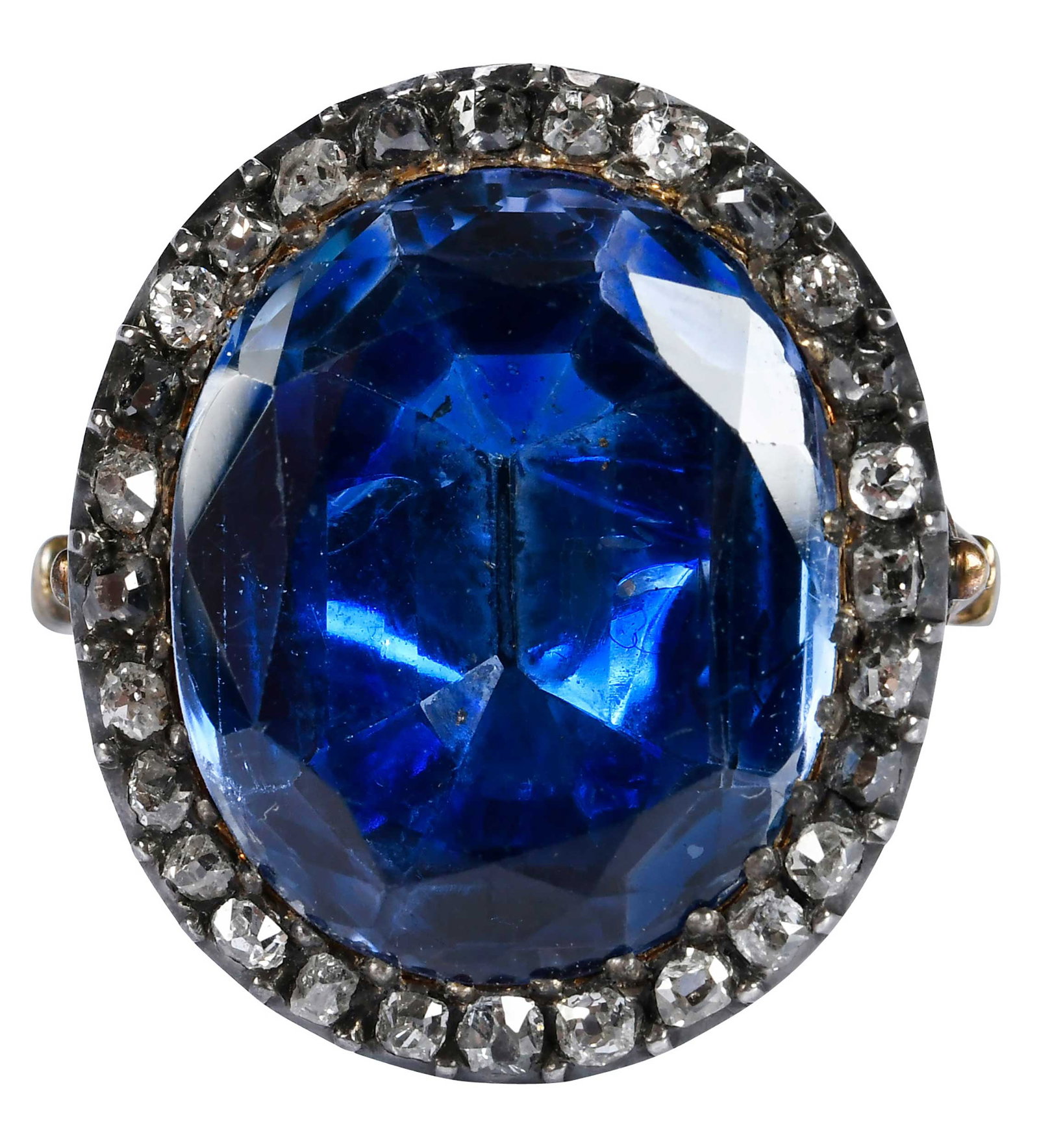 Victorian Blue Sapphire and Diamonds Ring: oval old cut blue sapphire, flat table, old cut diamond halo accents, foil closed back, ring and backing tests 18kt. yellow gold, paired with silver topped settings, approx. 22.0 x 19.0 mm overall des