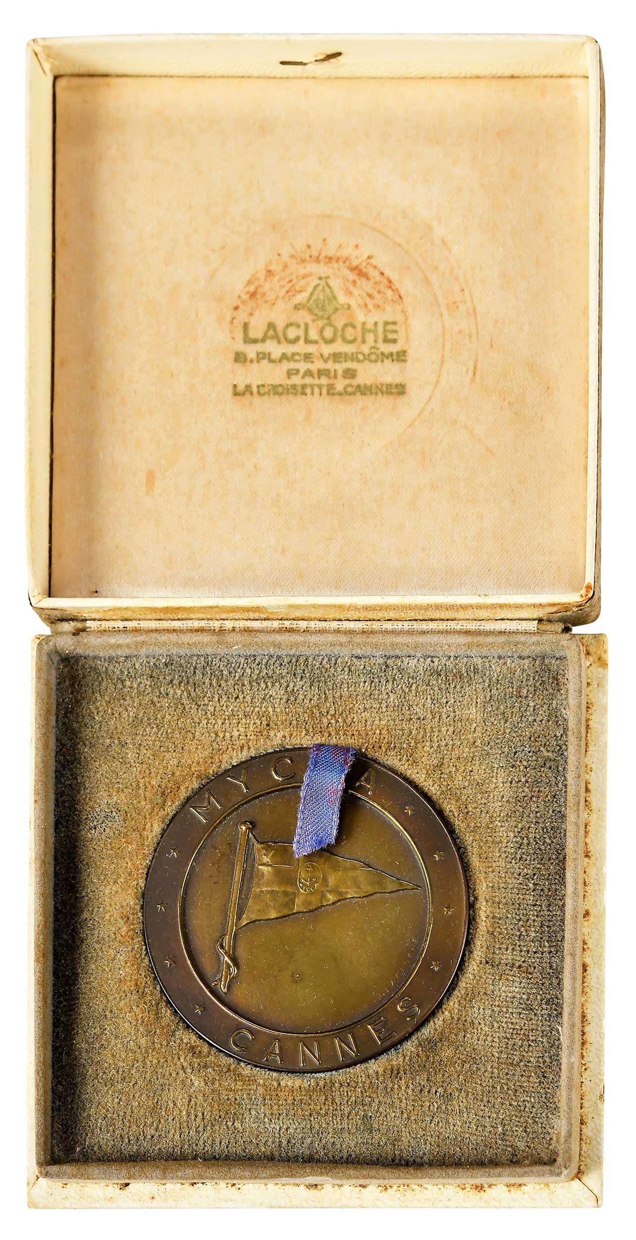 Motor Yacht Club de la Cote d'Azur Medal in Original Box: M.Y.C.C.A. Cannes medal, struck in bronze, signed "L. Lacloche", in felt interior box, with handwritten note on box "Aug 15, 1972 Awarded to Kathryn Colton", medal 50 mm diameter Provenance: Private