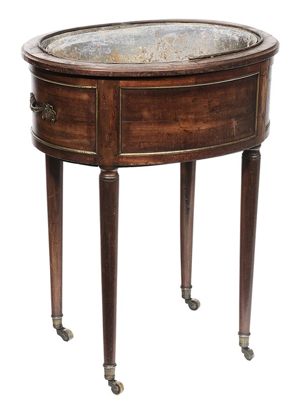 George III Mahogany Brass-Banded: Wine Cooler British, 19th century, figured mahogany oval frame, turned legs set with casters, lead liner, 29 x 22-1/2 x 17 in., finish and molding losses at top edges, now fitted with secondary liner,