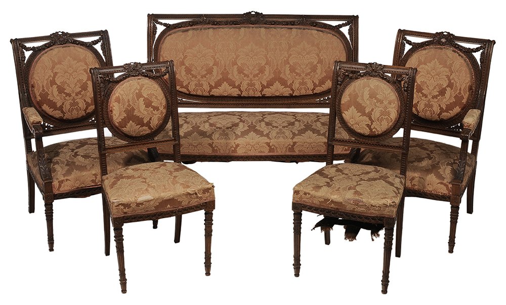 Louis XVI Style Finely Carved Walnut: Upholstered Parlor Suite French, late 19th/early 20th century, comprising a settee, two armchairs, two side chairs, each with well-executed ribbon, leaf and floral carving, damask upholstery, settee 4