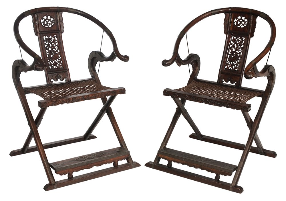 Pair Chinese Carved Hardwood: Folding Scholars' Chairs 20th century, each with yoke back, pierced dragon-carved splats, woven fiber seats and brass mounts, 41-3/4 x 29 x 27-1/4 in., one with cracks and separations at splat, other 