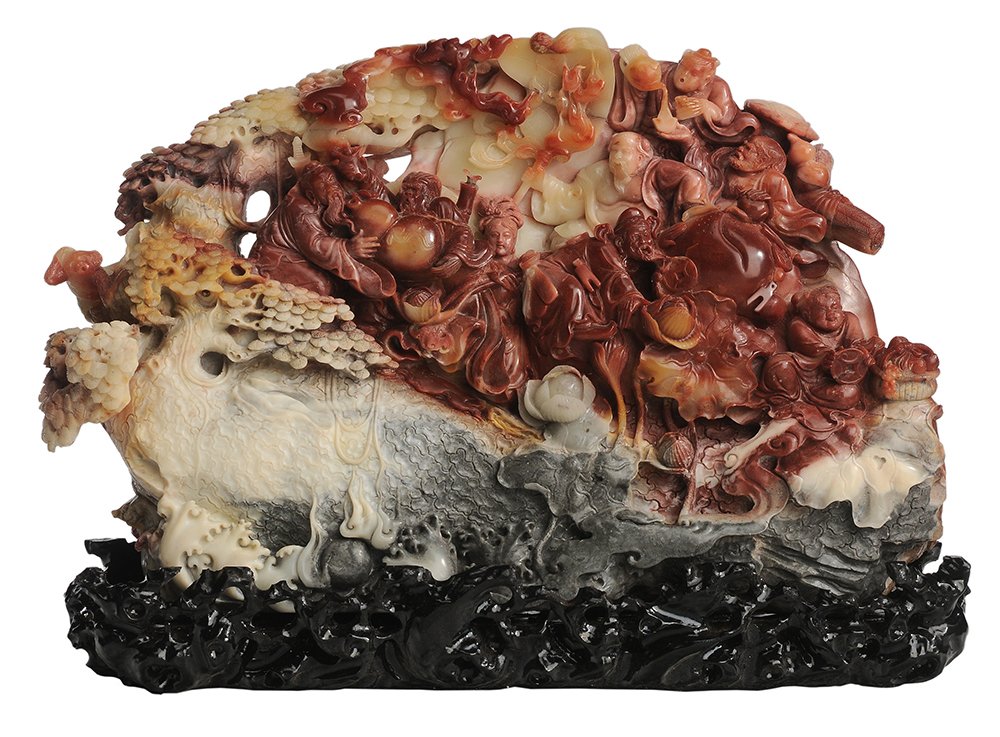 Finely Carved Figural Soapstone: Boulder Chinese, 20th century, colors ranging from rich red to ivory and gray, figures with auspicious symbols with trees and breaking waves in the foreground, set on a modern carved stand, 11 x 17 in