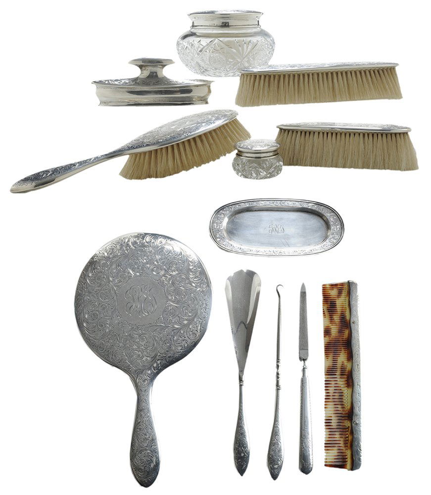 Eleven-Piece Sterling Dresser Set: Canadian/American, early 20th century, all with elaborate engraved floral and scroll decoration including 10-3/4 in. hand mirror, three brushes, two lidded jars with cut-glass bases, nail buffer with