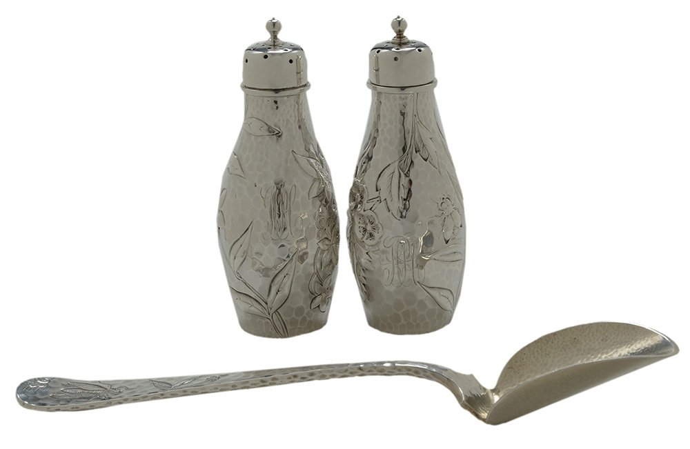 Three Pieces Dominick & Haff Japanese: Style Sterling Pieces American, late 19th century, all with hammered finish, dragonfly, insect and floral decoration, including pair salt and pepper casters, monogram, 4-3/4 in.; cheese scoop, gilt bo