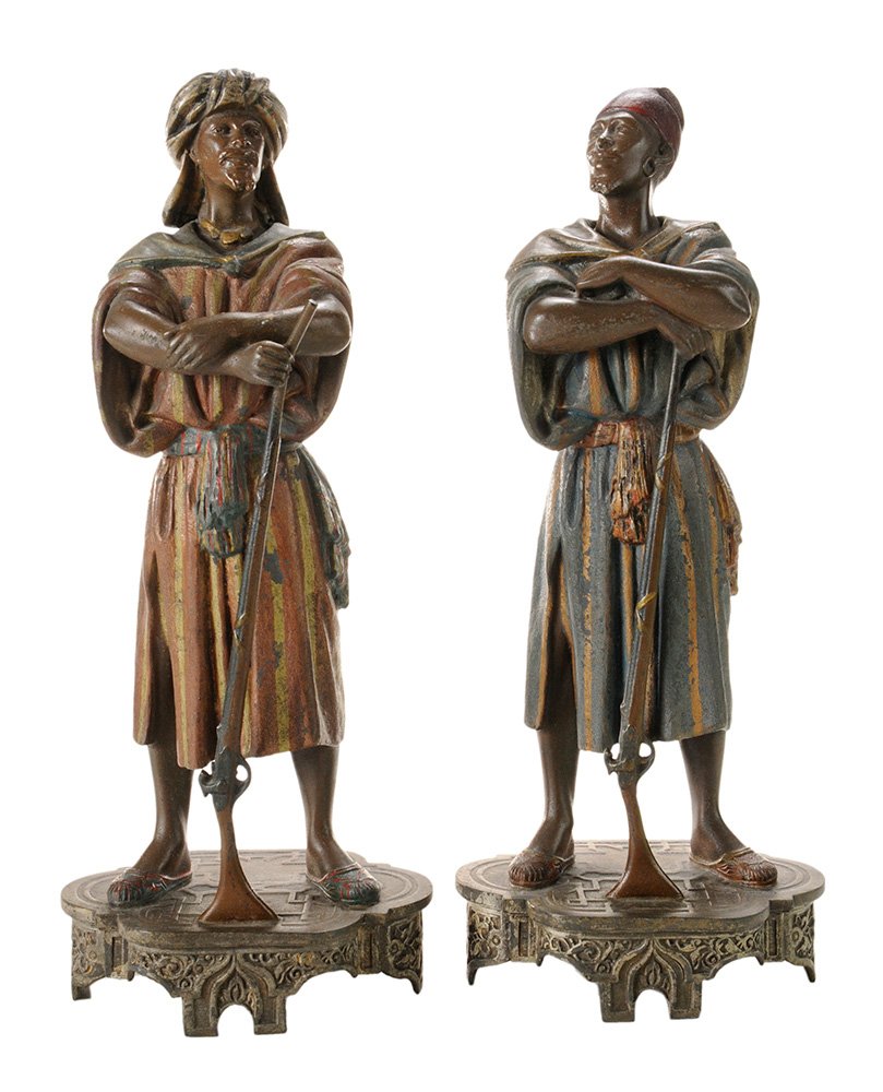 Pair Polychrome Decorated Spelter: Polychrome Figures Holding Rifles Continental, 19th century, polychrome decorated figures holding rifles, with head covers, colorful tunics and scarves, on raised platform bases, 16 in. one rifle bent