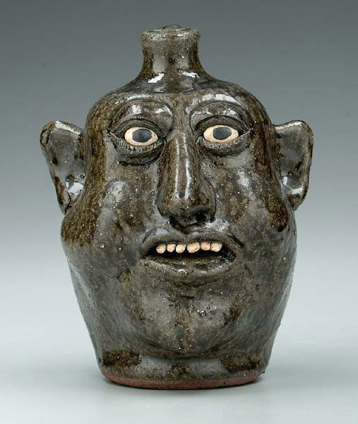 Lanier Meaders stoneware face jug,: mottled and runny dark olive alkaline glaze, bulging eyes, ceramic teeth, inscribed on base "Lanier Meaders" (Quillian Lanier Meaders, White County, Georgia, 1917-1998), 9 in.