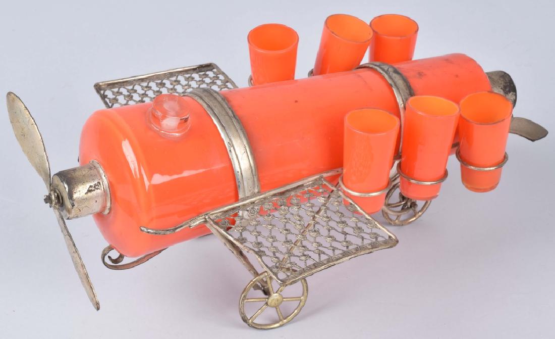 VINTAGE GLASS AIRPLANE LIQUOR DECANTER: Vintage Airplane Liquor Decanter. Orange glass decanter is the body of the airplane. It has metal wings, prop, tail, and wheels. Shot glasses are held in the wings. Very unique piece. 14" Excellent