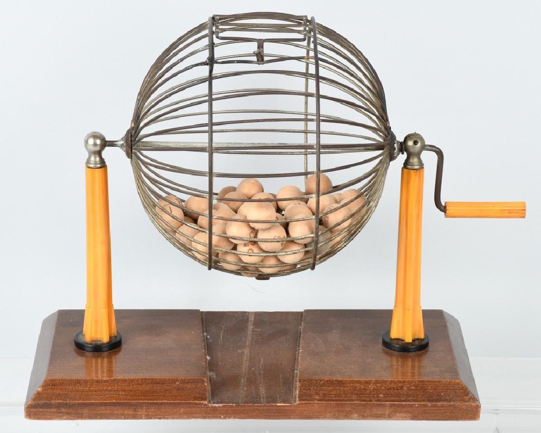 EARLY BAKELITE BINGO MACHINE CAGE & BALLS: Early Bingo Machine Cage with Balls. Wire cage with cast iron ball feeder. Has bakelite pillars holding the cage mounted on a wire base. Comes with all the wooden balls. 14" Excellent