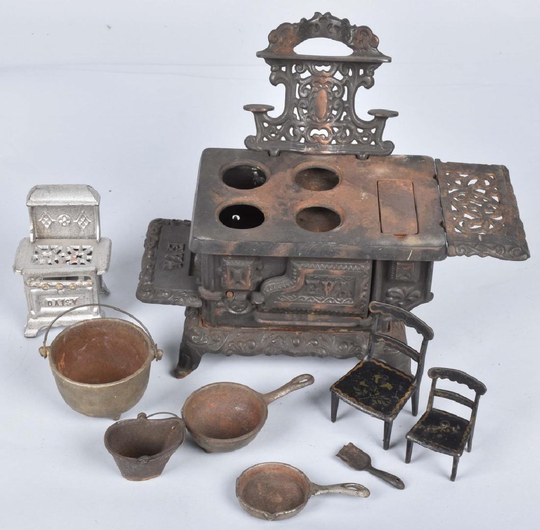 KENTON CAST IRON "EVA" TOY STOVE and MORE: Kenton stove measures 7 1/2" by 5" by 5". Lot includes cast iron kettles, 2 early Stevens cast iron chairs and a small A.C. Williams Daisy stove. Good-Very Good