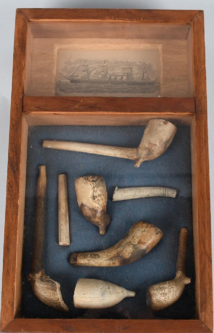 19th CENTURY DUG TRADE PIPES: Wonderful shadow box display of dug trade pipes. One has a sailing ship decoration. The condition varies. Also framed is a 4" by 2 1/2" advertisement for Inman Royal Mail Steamers Ship lines. Displays