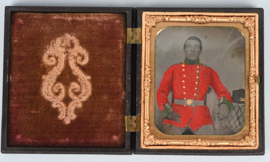1/6TH PLATE TINTED AMBROTYPE FOREIGN SOLDIER: Beautifully tinted ambrotype of a seated foreign soldier. His coat is tinted red with collar and cuffs tinted green and gold buttons. He is resting his arm on a table next to his headgear that has the