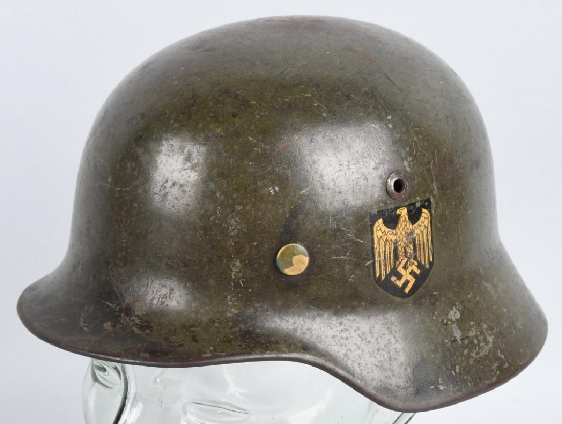 WWII NAZI GERMAN M 35 DOUBLE DECAL HELMET: M35 Sheet steel construction helmet retaining about 75% of its original smooth parade green paint. The left side of the helmet has a black lined, Wehrmacht eagle decal which is retained about 85%. The
